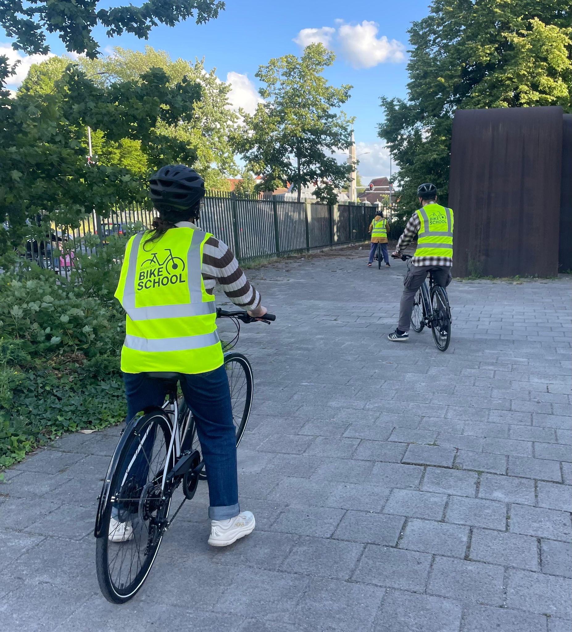 Volwassen van de Brainport Bike School oefenen met fietsen onder begeleiding van een instructeur.